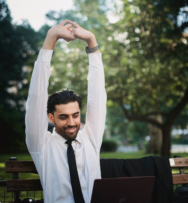 A person smiling and stretching in a park, feeling refreshed and balanced.